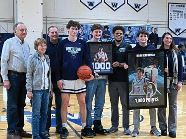 student posing in basketball uniform alongside members of family